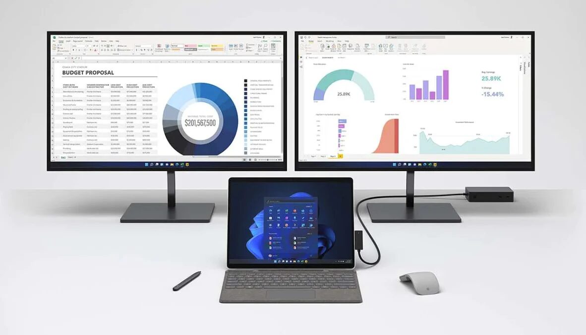 Два монитора Microsoft Surface Pro 8 с графиками и таблицами на экране, планшетное устройство в центре, мышь и стилус на столе