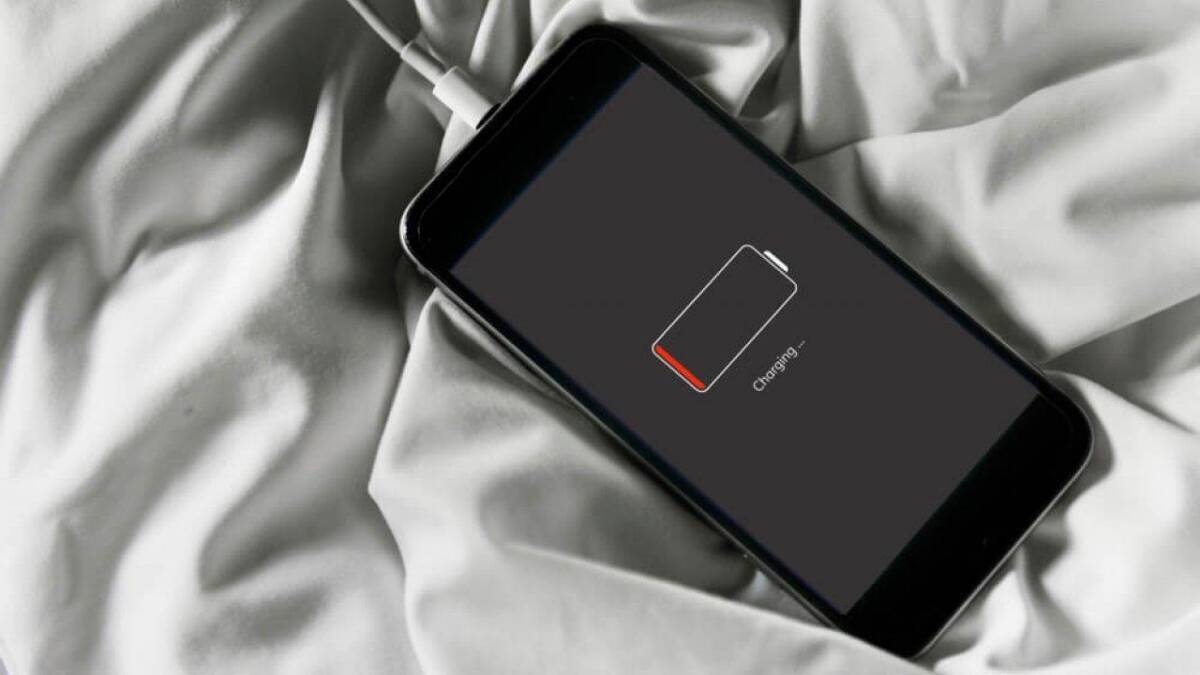 Смартфон подключен к зарядке, на экране показан индикатор уровня заряда батареи