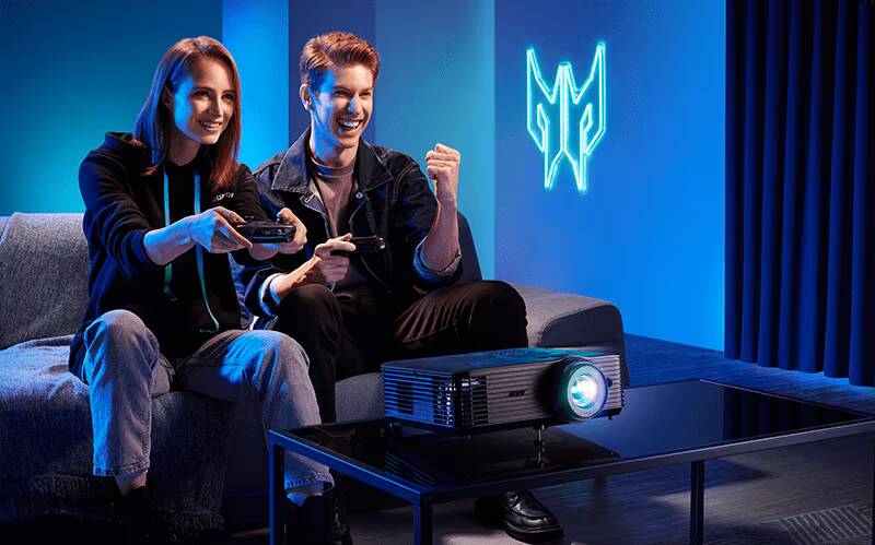 Acer дополняет линейку настольных игровых ПК новой мощной моделью Predator Orion 7000 3 Два человека играют на игровых контроллерах рядом с компьютером Acer Predator Orion 7000 на темной мебели с неоновым логотипом