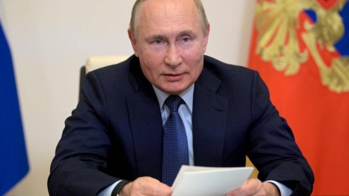 Владимир Путин на официальной встрече в деловом костюме, рядом белый лист на столе