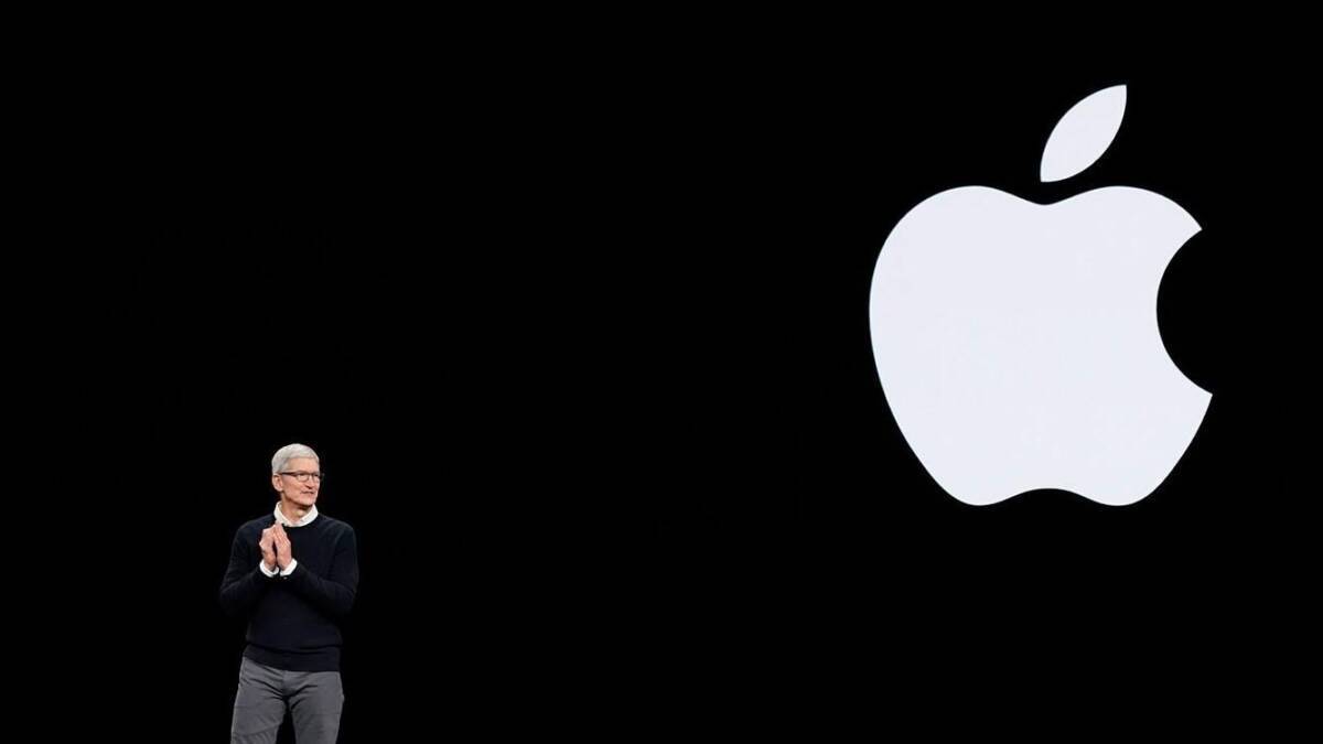 Человек на сцене с большим логотипом Apple и наушниками AirPods Pro 2