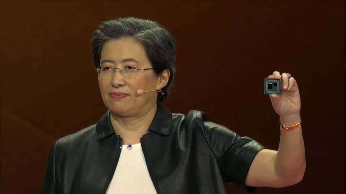 Женщина в очках показывает видеокарту и компоненты на презентации AMD Ryzen на фоне логотипа компании
