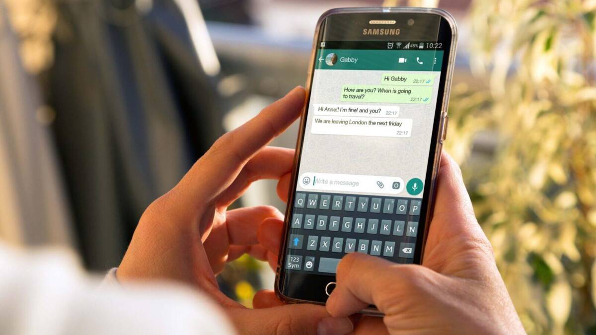 Рука держит смартфон Samsung с открытым WhatsApp