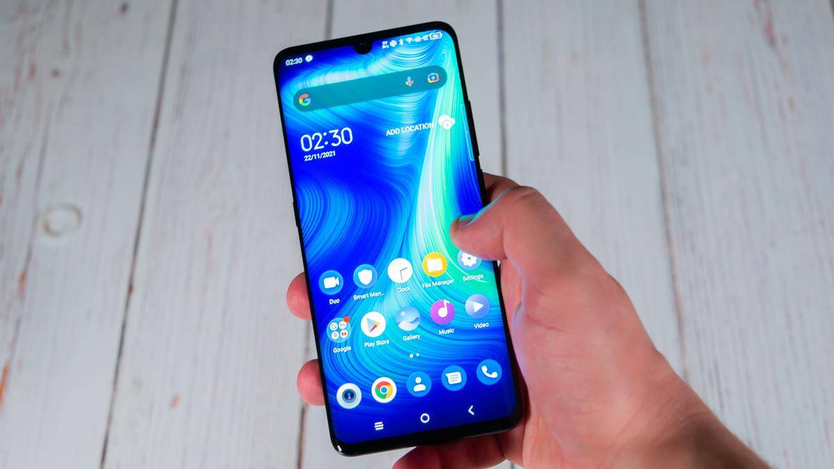 Обзор TCL 10 Pro: очень выгодный смартфон 25 Смартфон TCL 10 Pro в руке перед светлым деревянным фоном