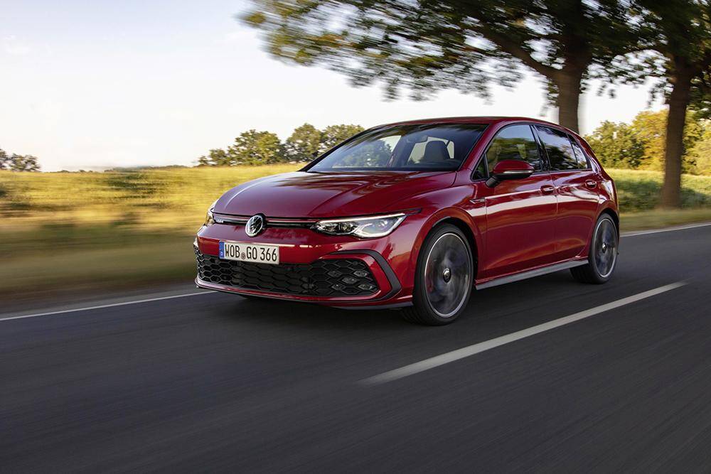Красный Volkswagen Golf движущийся по дороге в движении