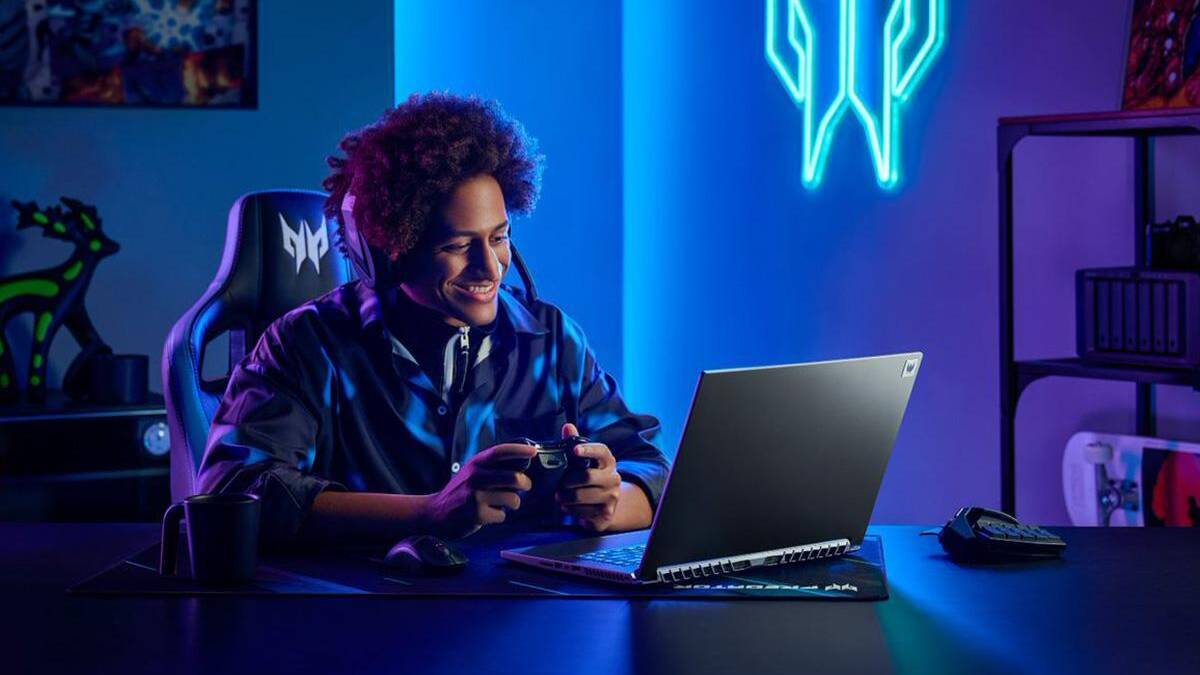Геймер с геймпадом за ноутбуком Acer Predator Triton 500 SE на рабочем столе