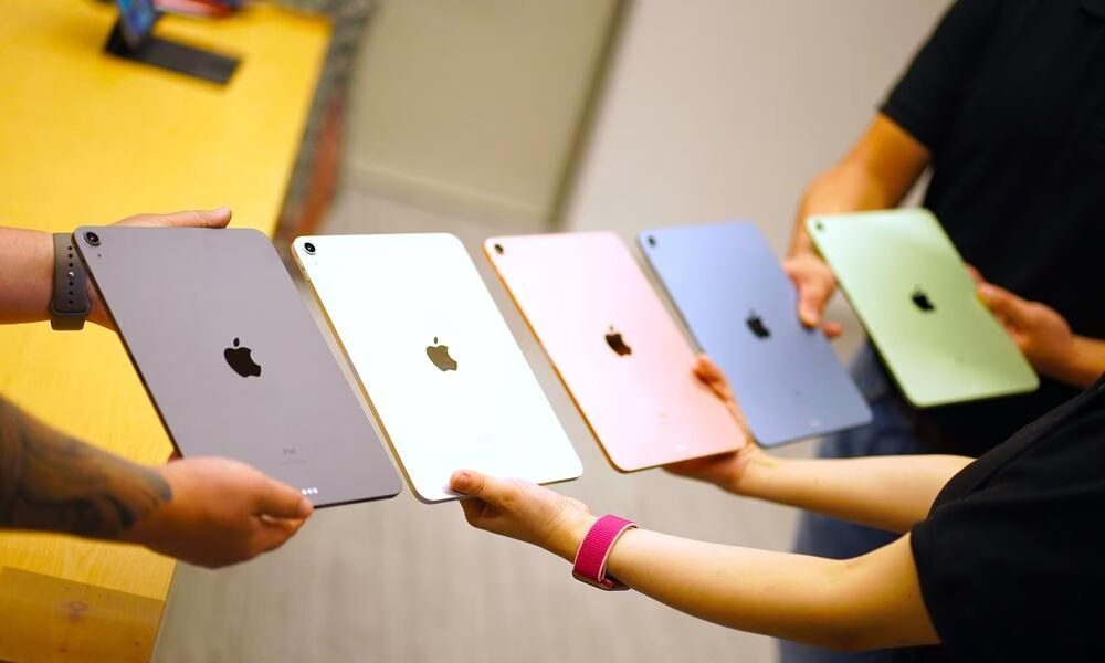 Цветные iPad Pro 2022 в руках людей на столе