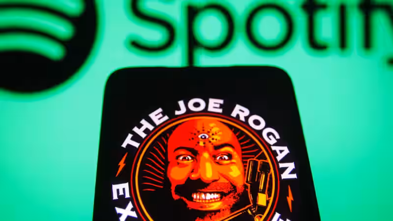 Экран смартфона с логотипом Spotify и обложкой The Joe Rogan Experience с Джо Роганом
