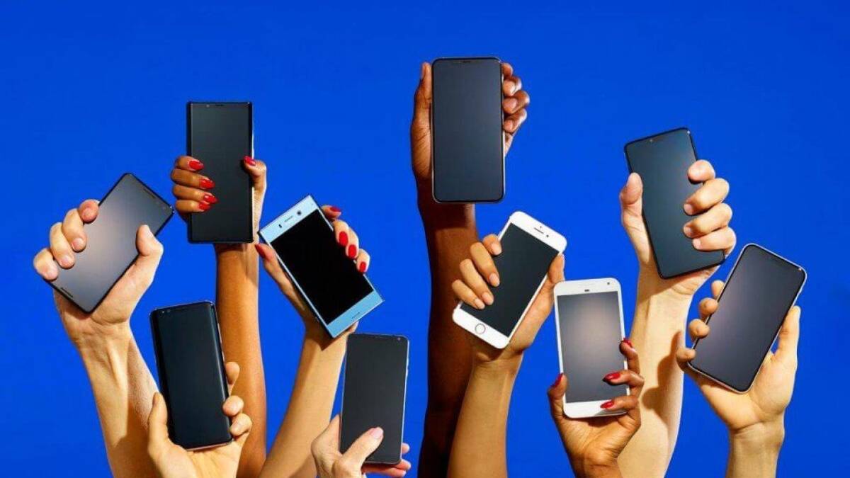 Apple iPhone 14 – самый ожидаемый смартфон 2022 года 5 Множество людей держат смартфоны Apple iPhone 14 на ярком голубом фоне