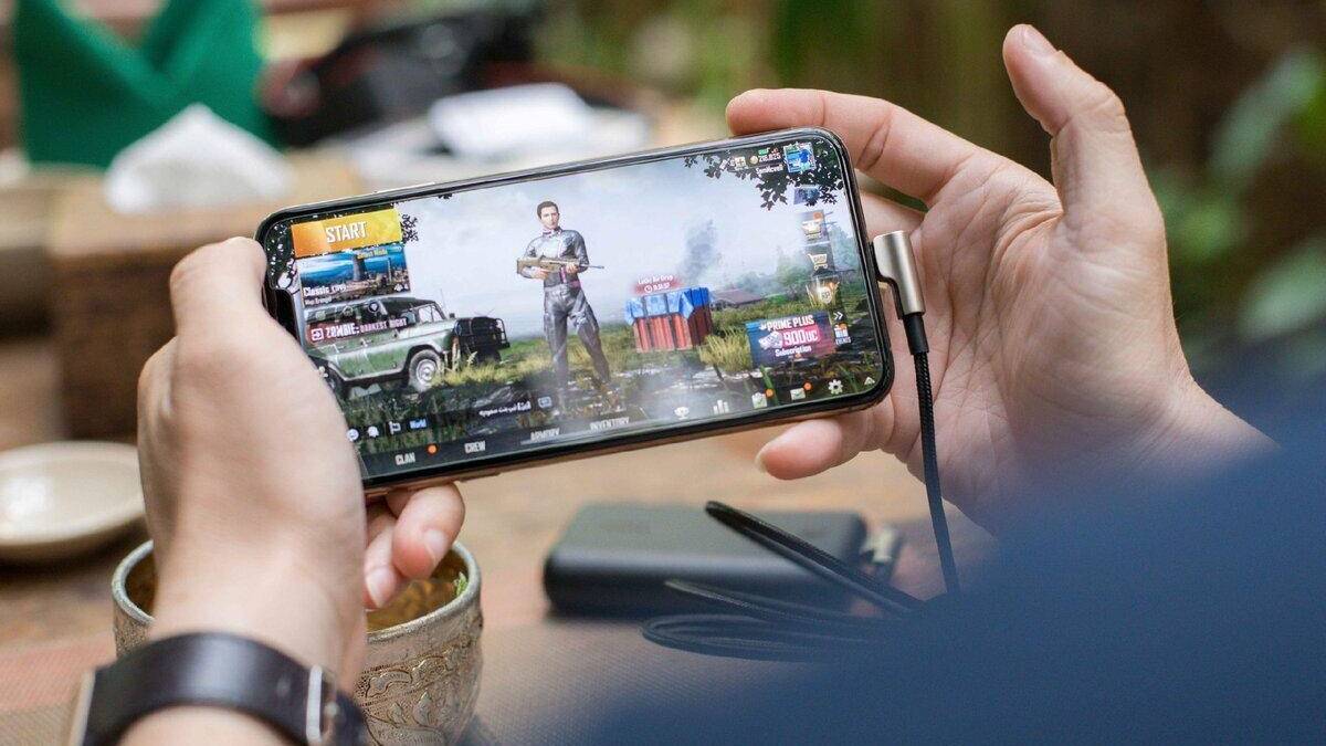 Игровое приложение на смартфоне: человек играет, подключив внешний аудиовход и наушники