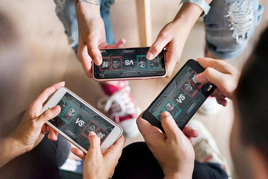 Три человека играют в мобильные игры на смартфонах