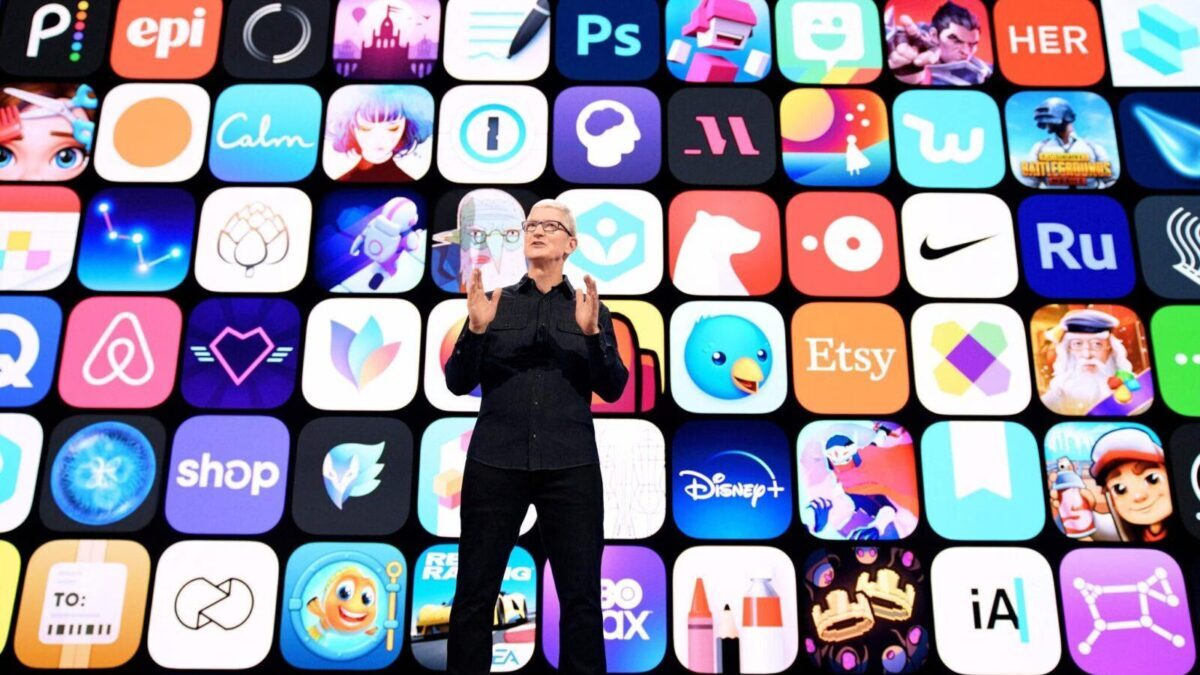 Человек на сцене рядом с большим экраном, демонстрация оплаты App Store через мобильный платёж