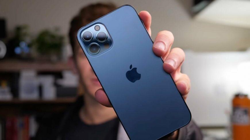 Человек держит в руке синий iPhone 13 с тройной камерой крупным планом