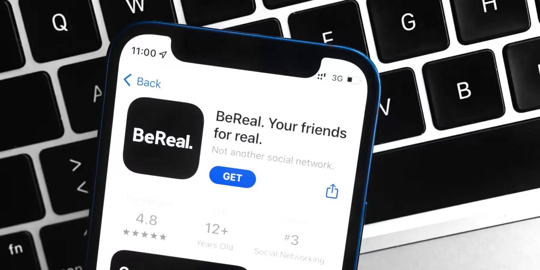 Экран смартфона с приложением BeReal на фоне клавиатуры ноутбука