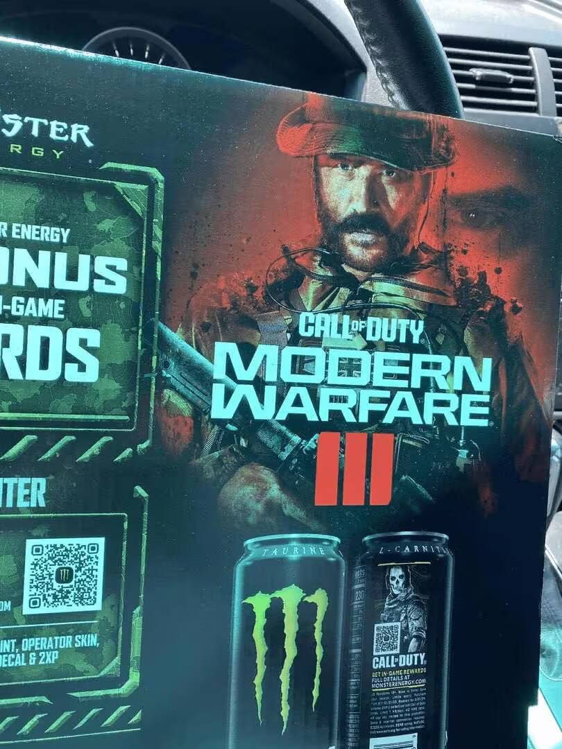 Коробка игры Call of Duty Modern Warfare 3 с изображением военного персонажа и энергетических напитков Monster