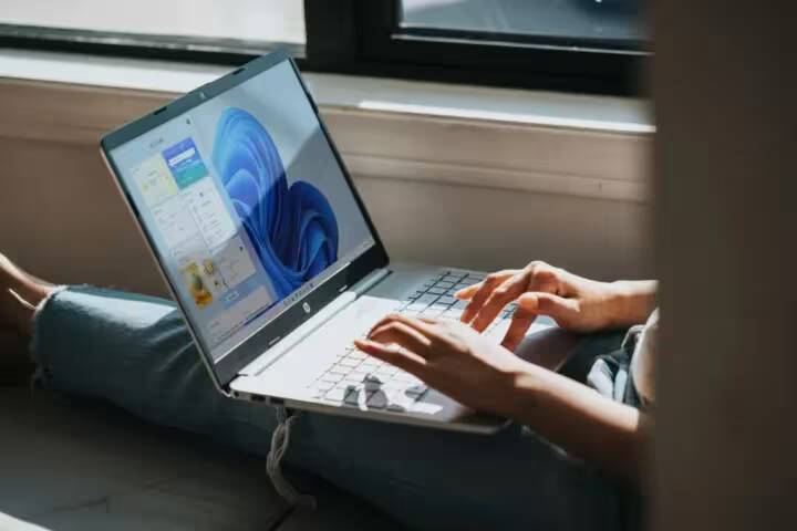 Человек использует ноутбук HP для работы у окна