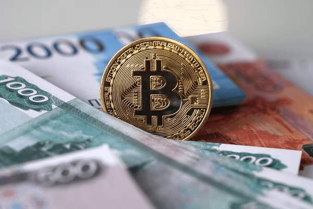 биткоин-символ на заднем плане с банкнотами российских рублей