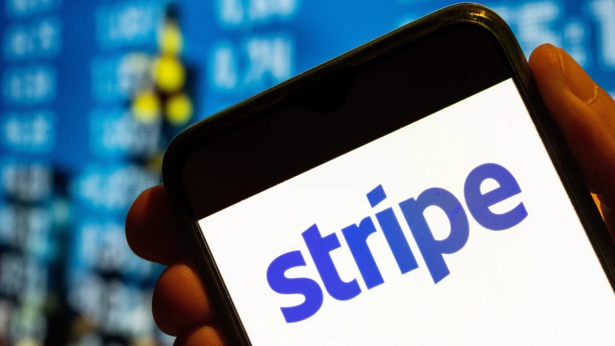 Рука держит смартфон с логотипом Stripe на экране в помещении