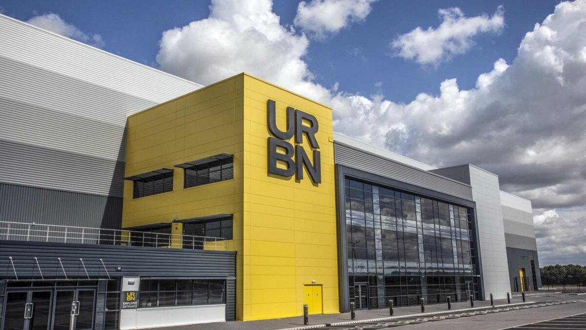 здание торгового центра URBN с ярко-желтой фасадной стеной и большими стеклянными окнами