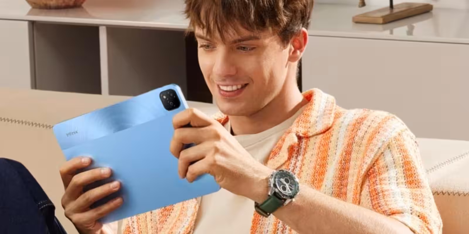 Парень держит синий планшет Infinix Xpad в руке