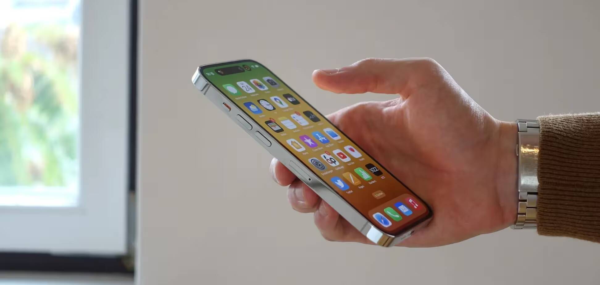 Рука держит iPhone с отображением интерфейса iOS