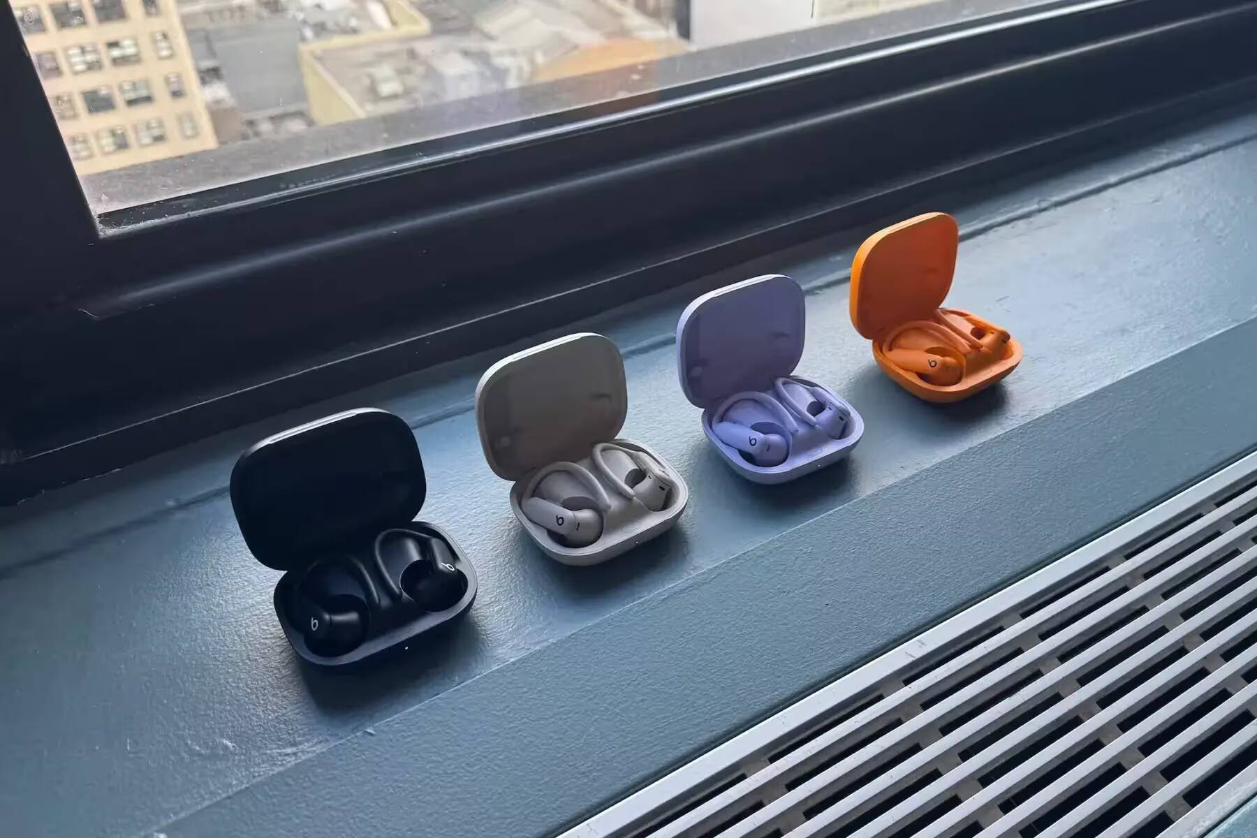 Четыре варианта наушников Apple AirPods Pro 2 и Beats Powerbeats Pro 2 в кейсах на подоконнике