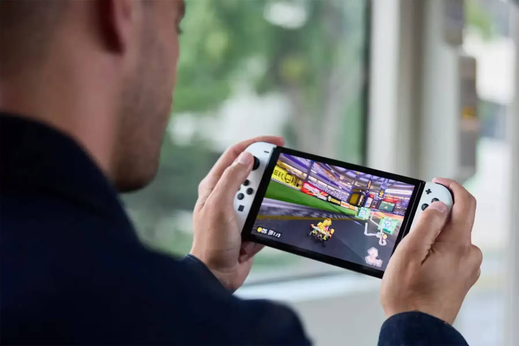 Человек держит игровой планшет Nintendo Switch на улице