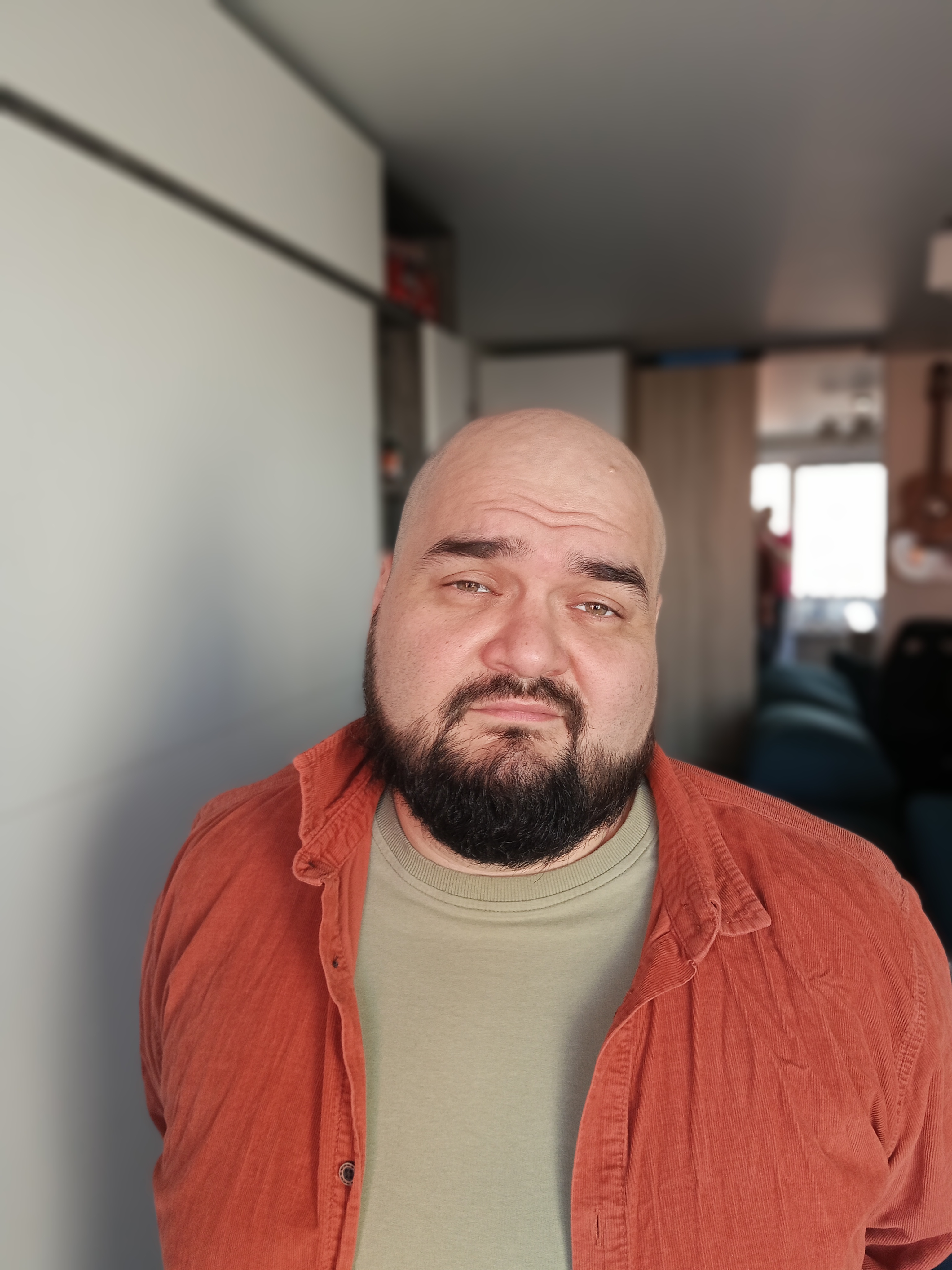 Мужчина с бородой в коричневой куртке и светлом свитере