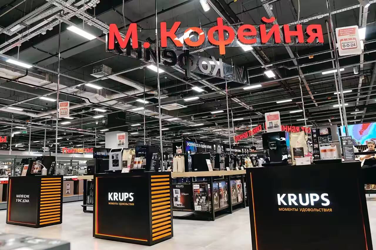 Кофемашины KRUPS на полке в магазине с яркими рекламными плакатами