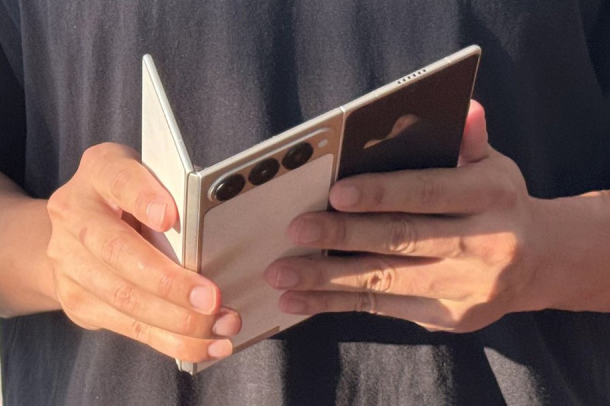 Человек держит смартфон Oppo Find X9 Ultra со штативом или аксессуаром для стабилизации