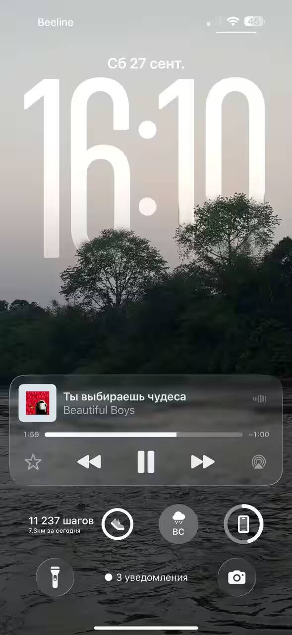 Обзор iOS 26: «жидкое стекло», фон в чате и многое другое 26 Экран iPhone с отображением времени и даты окно плеера музыки и уведомления
