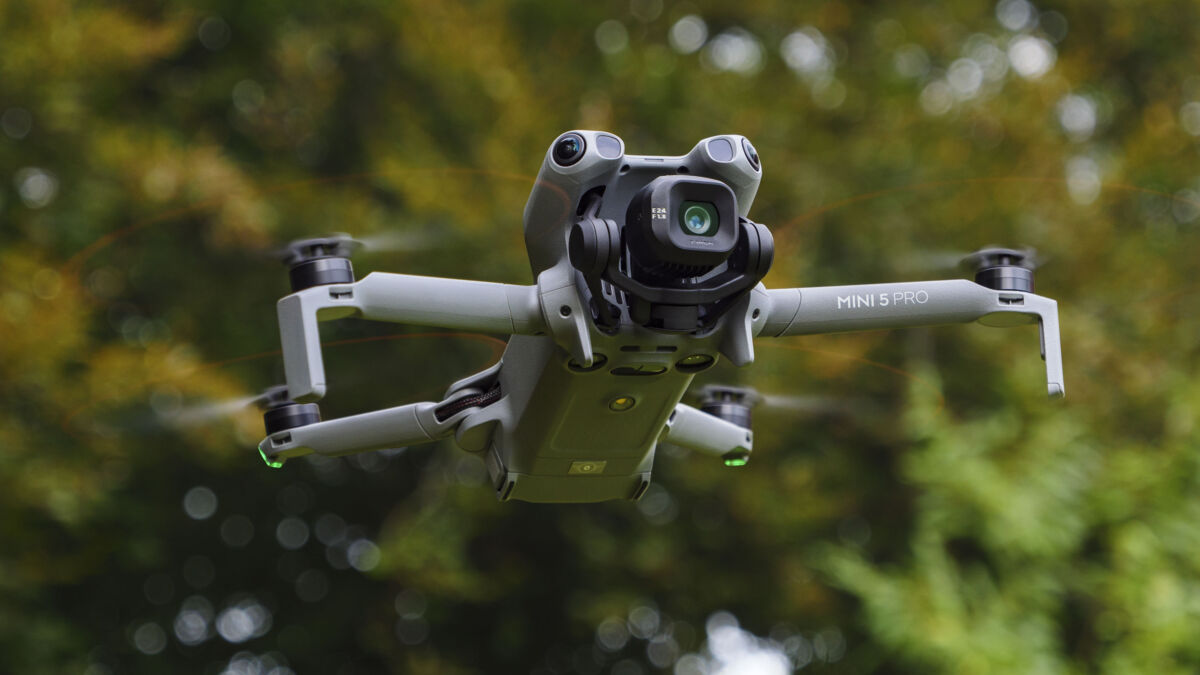 Дрон DJI Mini 5 Pro с камерой в полёте среди деревьев, вид с воздуха