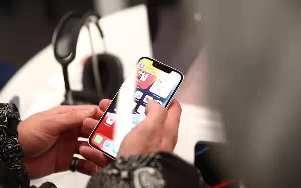 Apple хочет добавить в iPhone больше рекламы 2 Человек держит iPhone с открытым экраном, показывающим домашний интерфейс