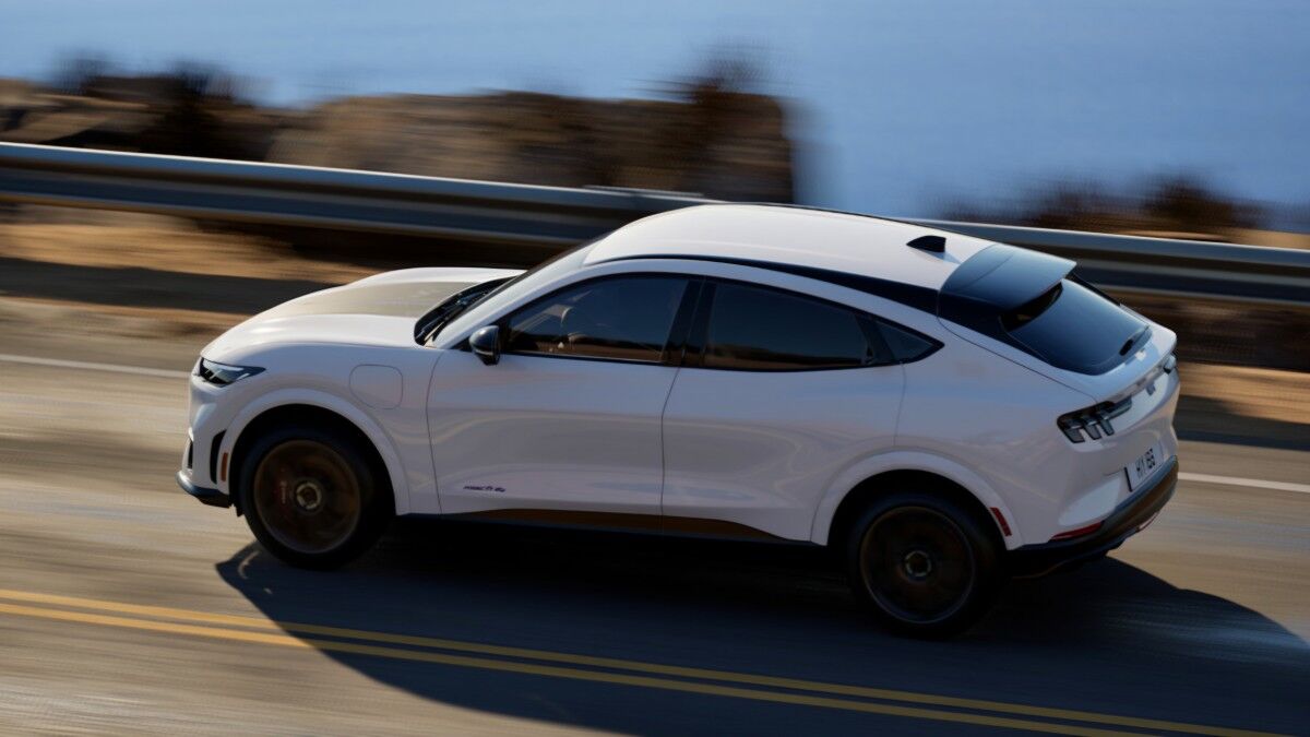 Белый Ford Mustang Mach-E на дороге по крутой поворот