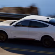 Белый Ford Mustang Mach-E на дороге по крутой поворот