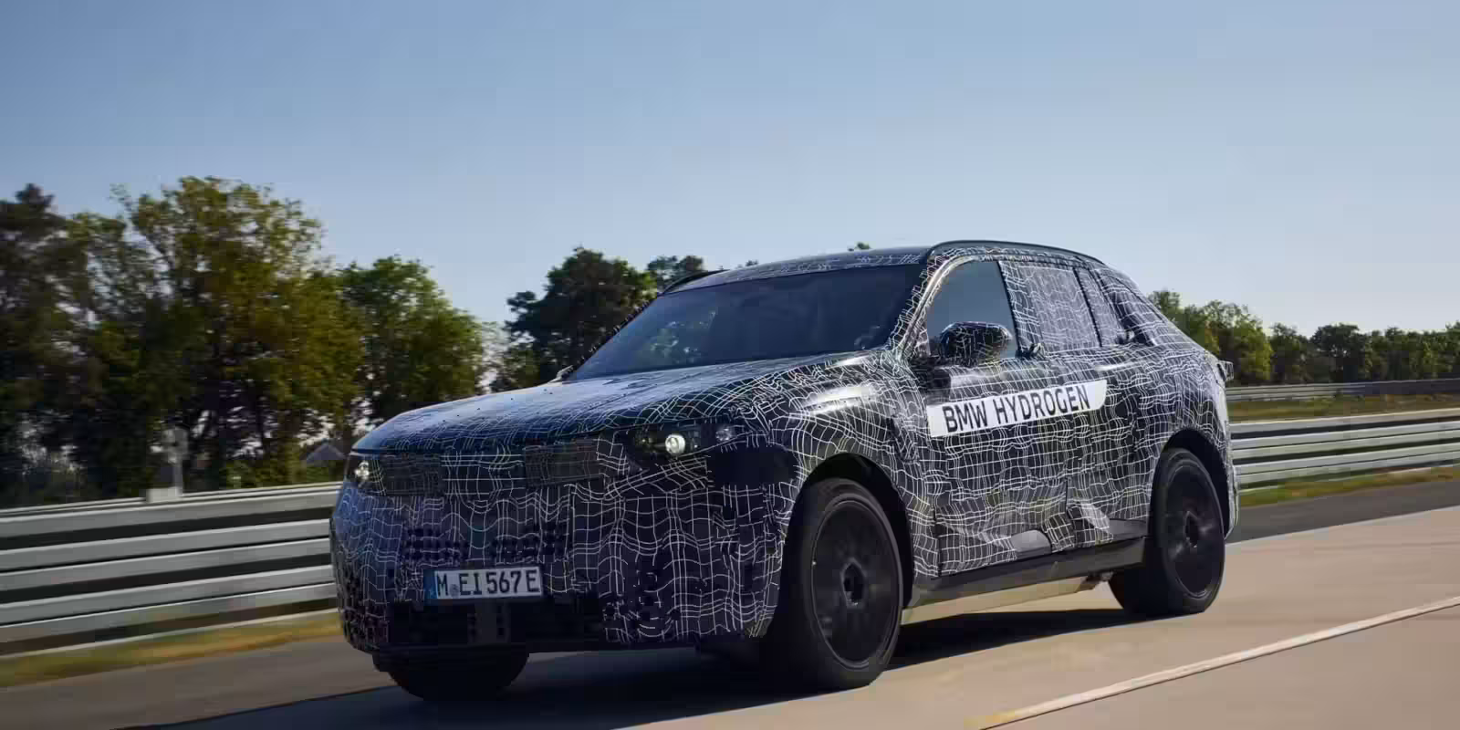 Тестовый прототип BMW Hydrogen на дороге с зеленью