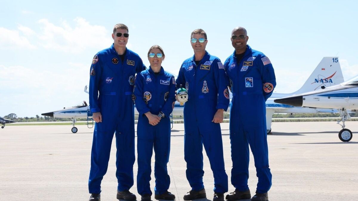 Четыре астронавта в синих скафандрах у самолетов