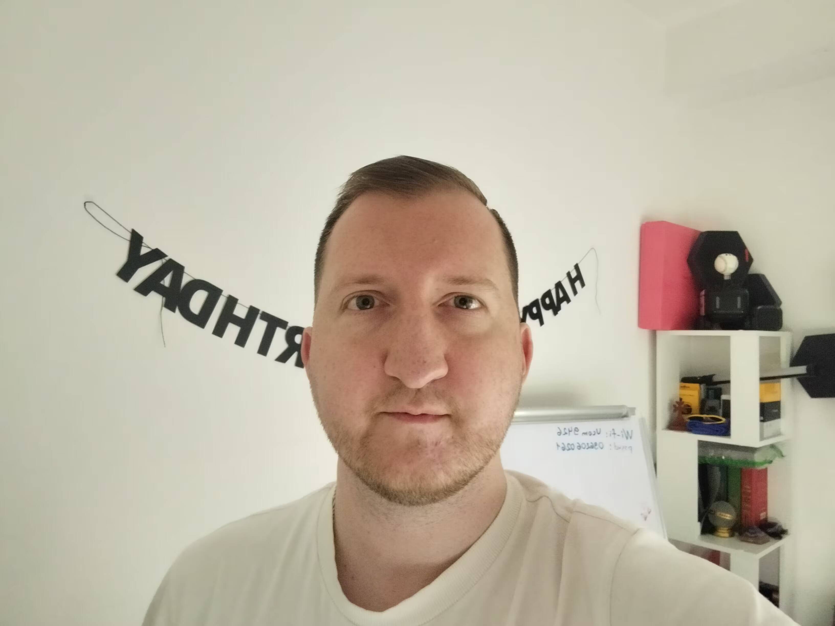 Мужчина делает селфи с смартфоном Realme C85 на фоне белой стены