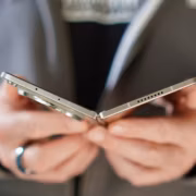 человек держит смартфон с металлическим корпусом MacBook Neo