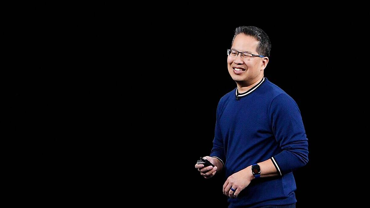 Человек в синем свитере и очках держит телефон