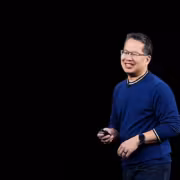 Человек в синем свитере и очках держит телефон