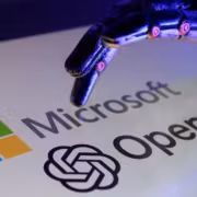 Рука робота, взаимодействующая с логотипами Microsoft и OpenAI