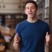 Мужчина говорит в библиотеке без пиджака