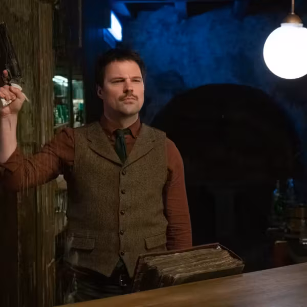 Мужчина стоит в баре с телефоном из статьи