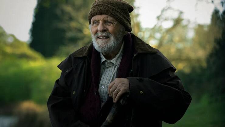 Пожилой мужчина в шапке и куртке в лесу посторонний предмет