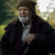 Пожилой мужчина в шапке и куртке в лесу посторонний предмет