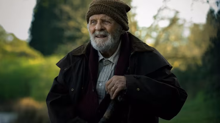 Пожилой мужчина в шапке и куртке в лесу посторонний предмет