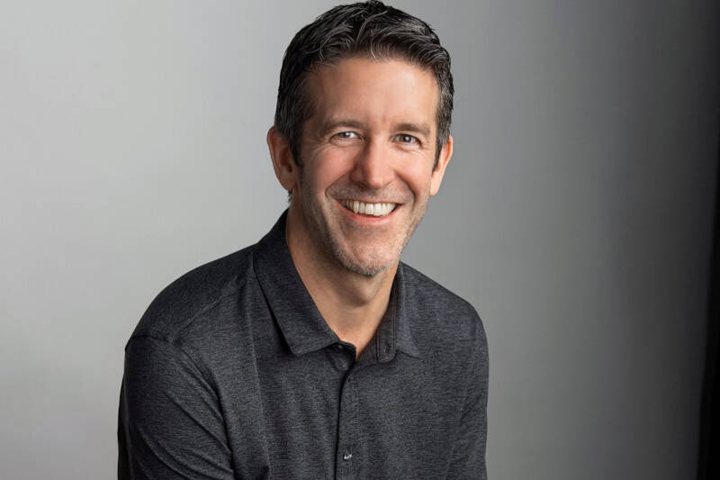 Улыбающийся мужчина в серой рубашке на сером фоне