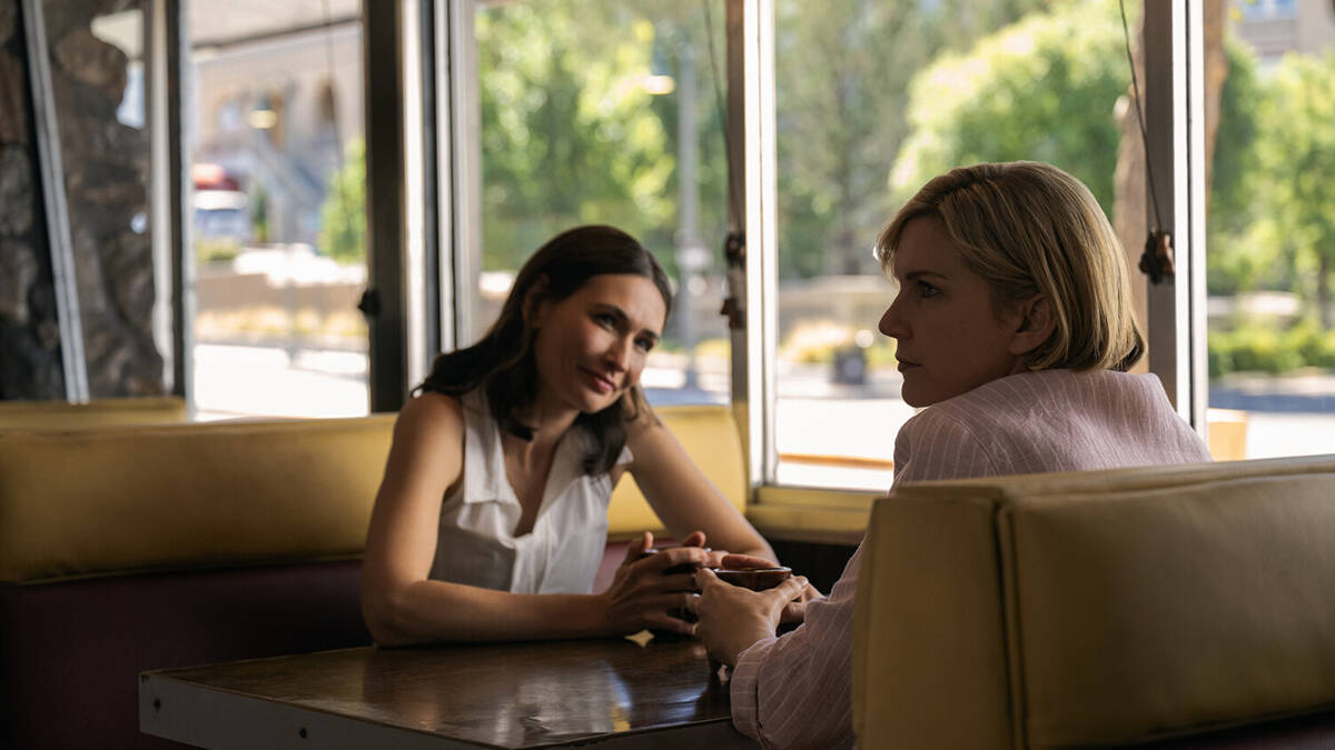 Две женщины общаются за столом в кафе «Одна из многих»