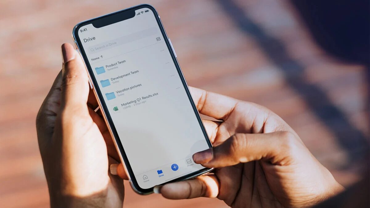 Человек держит iPhone с открытым облачным хранилищем Internxt